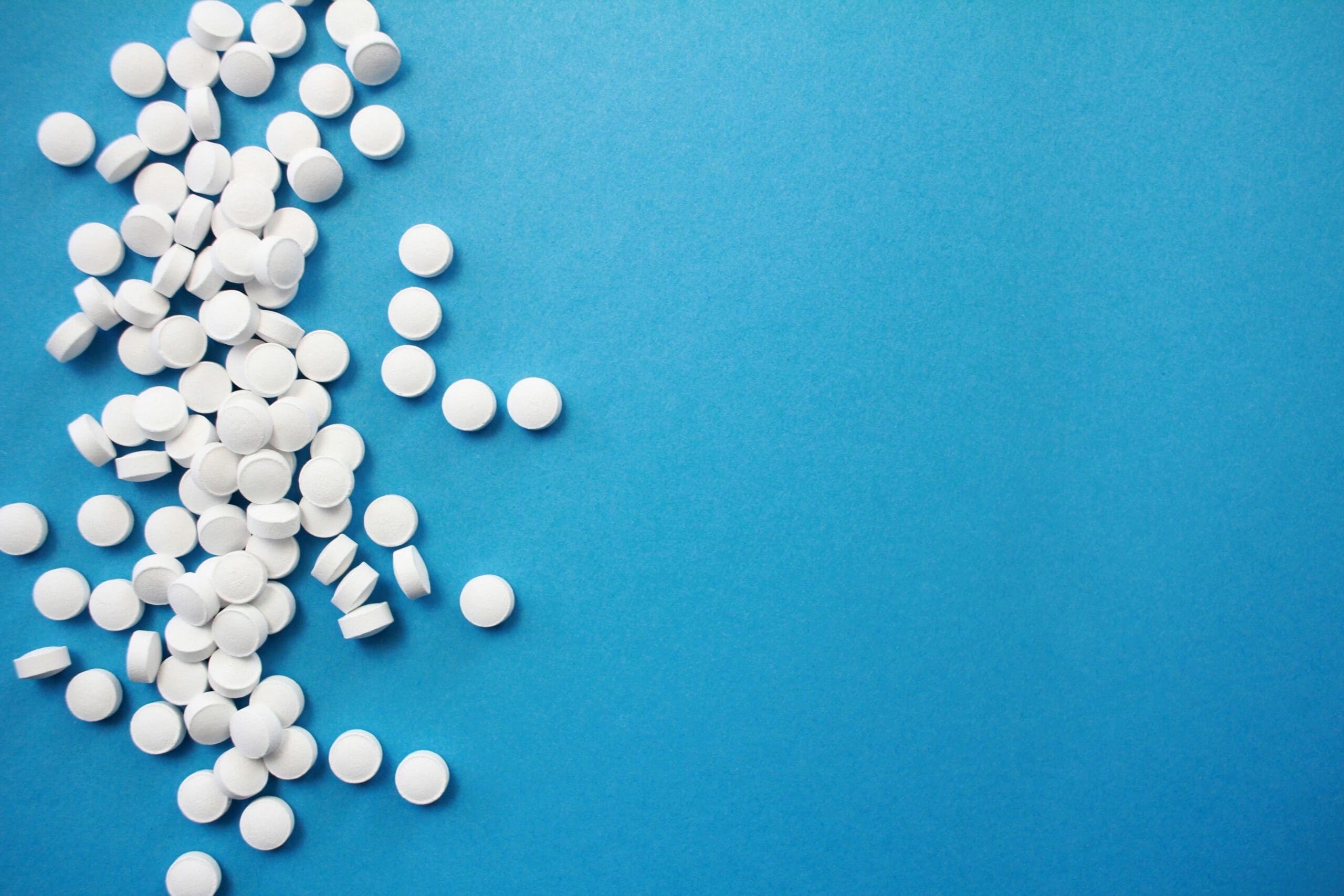 White weight loss pills on a blue background representing oral GLP-1 medication like Foundayo