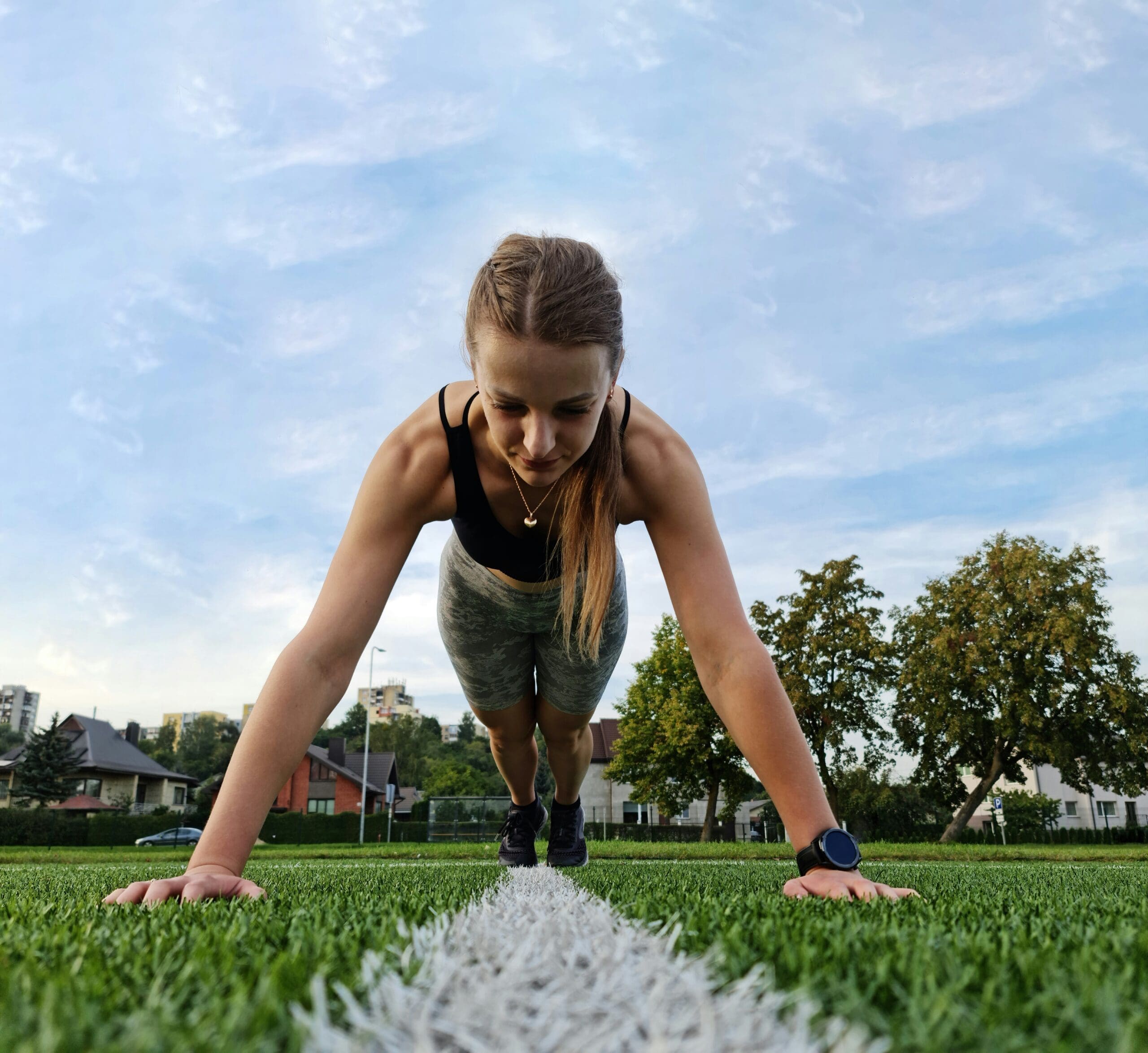 Woman doing a push-up outdoors on grass demonstrating upper body strength and fitness