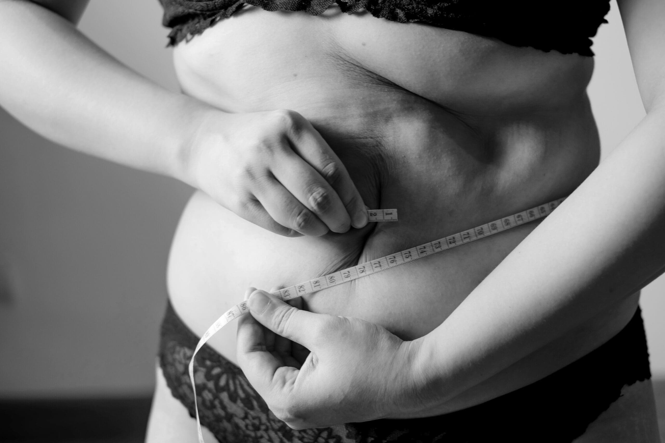 Woman measuring abdominal fat with tape, representing semaglutide not working and weight loss challenges